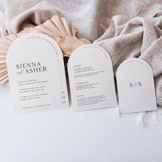 three wedding programs are laid out on a bed with a ruffled blanket and fan