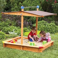 two children playing in a sandbox on the grass