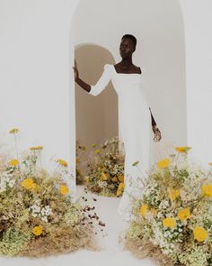 a woman in a white dress standing next to flowers