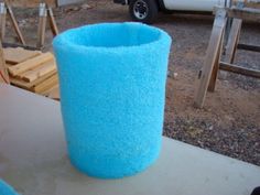 a large blue cup sitting on top of a table next to a white truck in the background