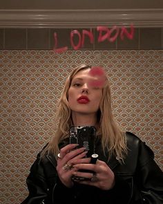 a woman taking a selfie in front of a mirror with the word london painted on it