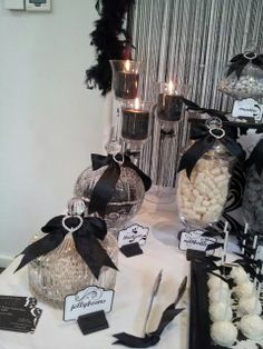 a table topped with lots of different types of candies and candy bar items on top of a white cloth covered table