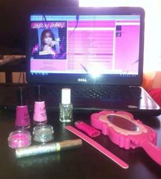 a laptop computer sitting on top of a desk next to nail polish and other items