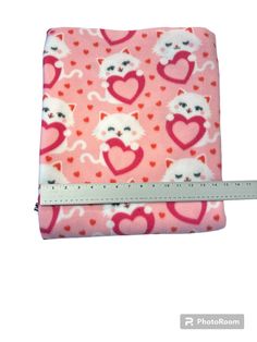 a pink wallet with hearts and cats printed on the front, sitting next to a ruler