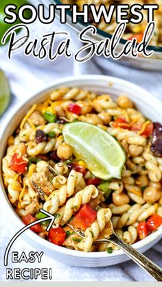 a bowl filled with pasta salad next to a lime and some other food on the table