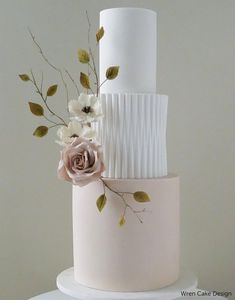 a three tiered wedding cake with flowers on top