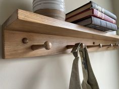 a wooden shelf with two hooks and some books on top of it next to a wall