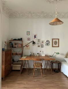 a room with a bed, desk and chair in it next to a lamp hanging from the ceiling