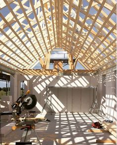 the inside of a building that is being built with wooden beams and construction equipment on the floor