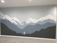 an empty room with mountains painted on the wall and carpeted flooring in front of it