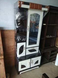 an oven is wrapped in plastic and sits on top of a bookcase, next to other cabinets