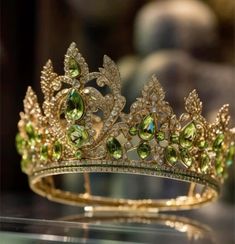 a gold tiara with green and white stones on it's headpieces