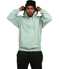 a man in a green hoodie is holding his hands on his head and looking at the camera