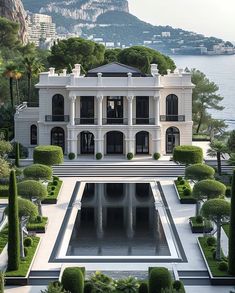 a large white house with lots of trees and bushes in front of the water's edge