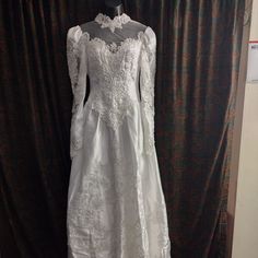 a white wedding dress on display in front of a curtain