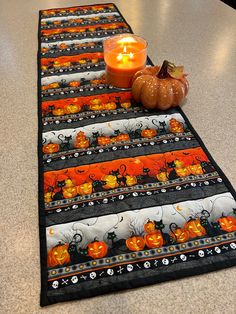 a table runner with pumpkins and candles on it in front of a candle holder