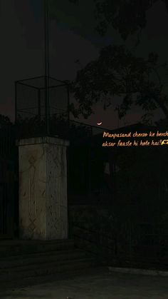 a man standing in front of a gate at night with a quote written on it