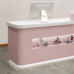 a pink and white counter with toy animals on the shelf next to an apple computer