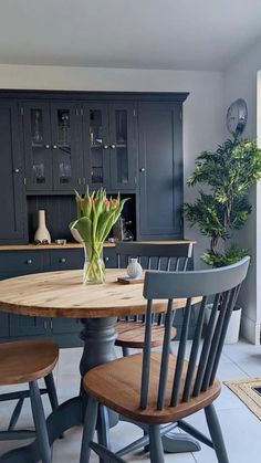 a kitchen table with four chairs and a potted plant in the middle of it