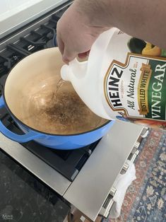 a person pouring something into a pot on top of a stove with the lid open