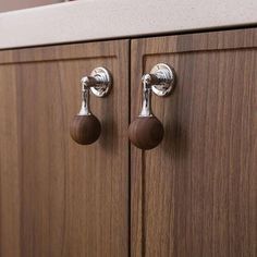 two wooden handles and knobs on the side of a brown cabinet with wood grained doors