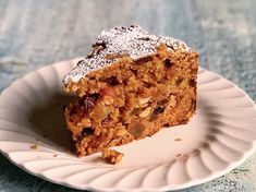 a piece of cake on a plate with powdered sugar and raisins around it