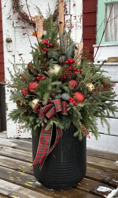 a potted plant with red berries and greenery in it on a wooden table