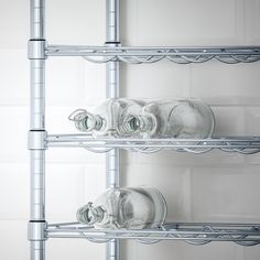 three glass bottles sitting on top of metal shelves