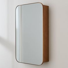 a mirror mounted to the side of a wall next to a light fixture on a white wall