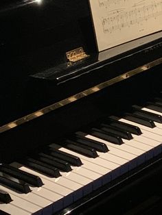 a black piano with sheet music on it's back and white keys in the foreground