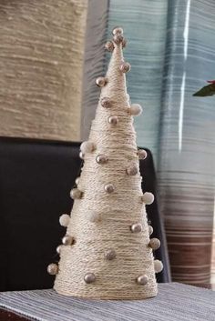 a white christmas tree made out of twine and buttons on a table next to a vase