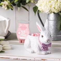 a white rabbit figurine sitting on top of a table next to flowers and candles