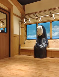 a black and white statue sitting on top of a wooden floor next to a window