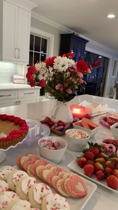 a table filled with desserts and flowers in vases on top of each other