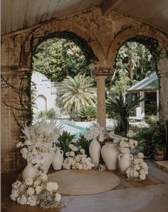 white vases and flowers are arranged on the floor in front of an arched doorway