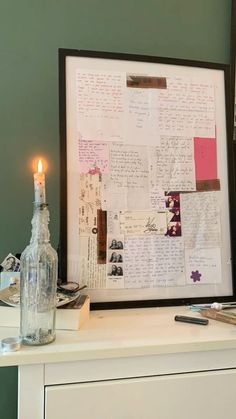 a table with a lit candle and a framed piece of paper on top of it