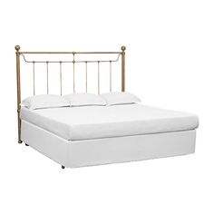 the bed frame is made up with white sheets and gold metal headboard, along with two pillows