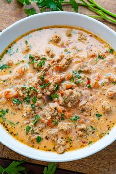 a white bowl filled with meat and vegetable soup on top of a wooden cutting board