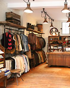 a clothing store filled with lots of different types of clothes and lamps hanging from the ceiling