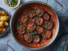 a pan filled with meatballs and sauce next to other food items on a table