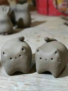 two clay cats sitting next to each other on a table