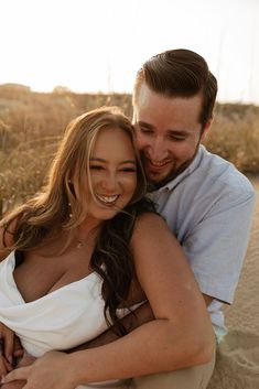 a man and woman hugging each other on the beach