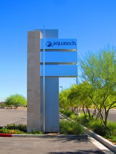 an aquatech sign in front of a parking lot with trees and bushes around it