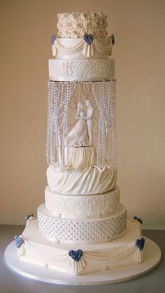 a three tiered wedding cake with white frosting and blue flowers on the top