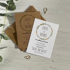 two wedding cards with the words daisy and bruno on them next to some greenery