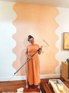 a woman in an orange dress holding a paint roller