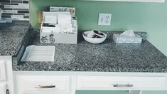 there is a bowl on the counter top in this kitchen with green walls and white cabinets