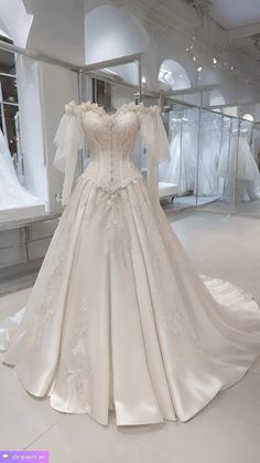 a white wedding dress on display in a room filled with mannequins and dresses