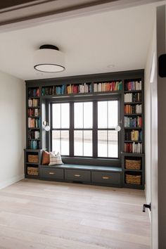 an empty room with bookshelves full of books and baskets on the windowsill