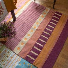 a potted plant sitting on top of a wooden floor next to a colorful rug